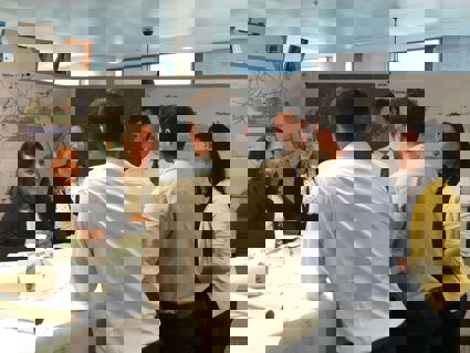 Six professionals standing around a table having a discussion