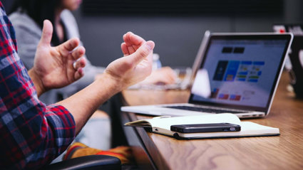 Two people sitting at a table with laptops.