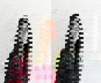 Woman standing in front of a white board, looking into the camera