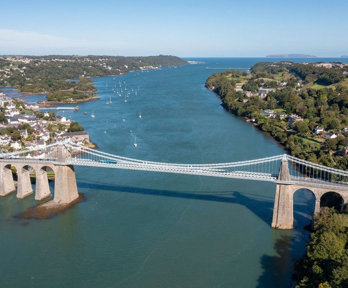 Aerial view of the Menai bridge above large blue strait.