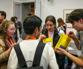 Four people at a conference standing in a circle. The two on the right each hold a bag that says 'firedepot'. The two on the left are watching them open the bags.
