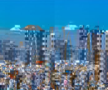 Skyline of Tokyo on a bright sunny day with in the background the snow capped top of Mount Fuji.