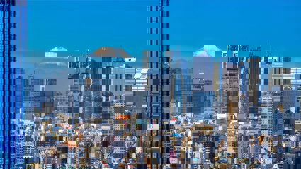 Skyline of Tokyo on a bright sunny day with in the background the snow capped top of Mount Fuji.