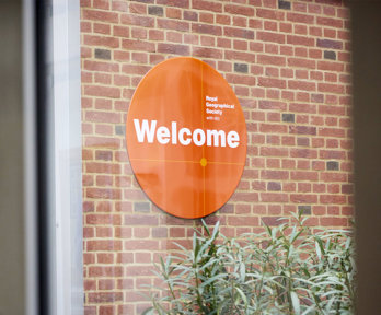 Welcome sign of the Royal Geographical Society (with IBG) seen through a window.