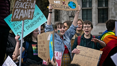 Teenagers at climate protest holding cardboard signs.