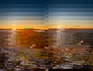 Gray stones in moorland with whote house in the distance