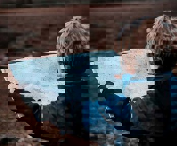 A young boy in the outdoors holding a map