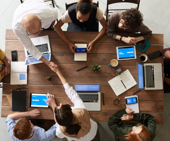 Aerial view of people working at laptops around a table.